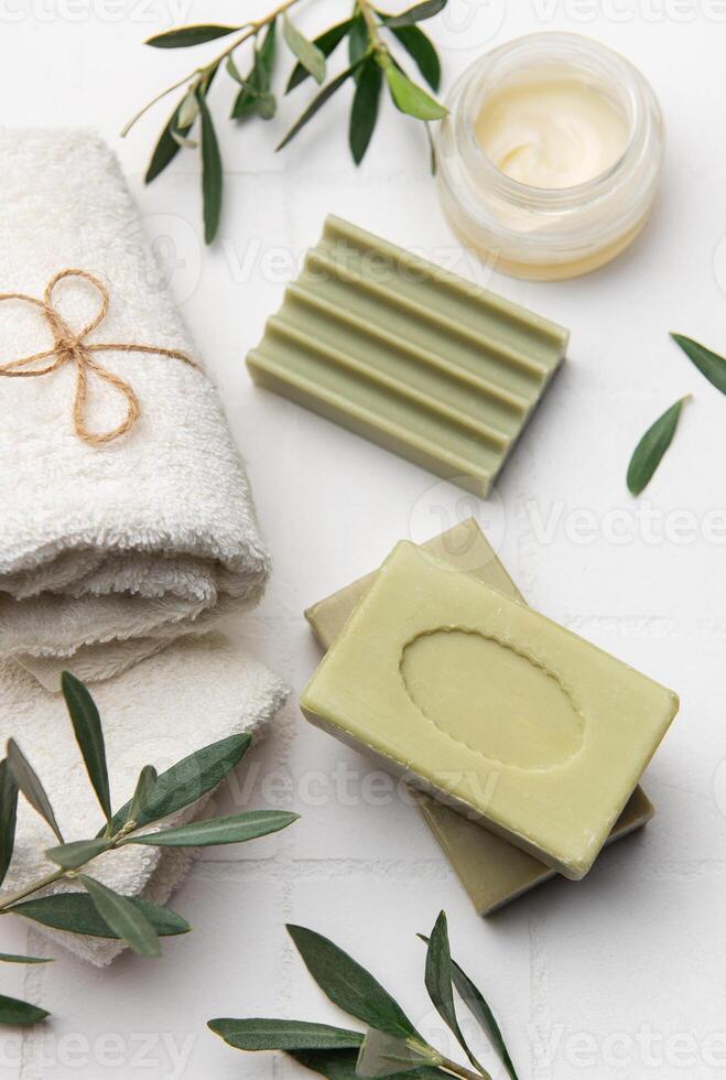 Olive soap bars, moisturizing cream and towels promoting natural body care photo