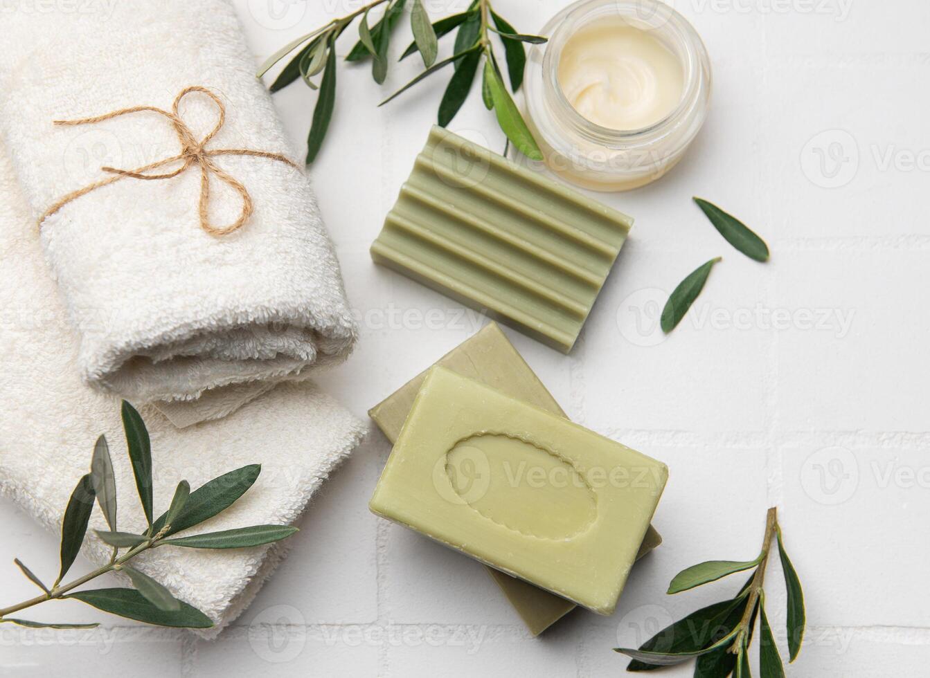 Olive soap bars, moisturizing cream and towels promoting body care photo
