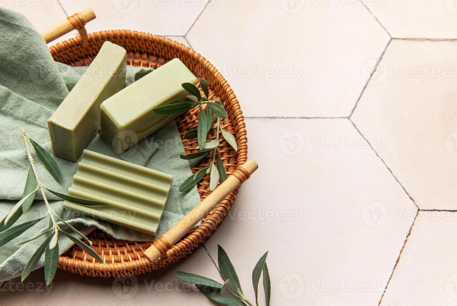 Olive soap bars with olive branches resting on a woven tray photo