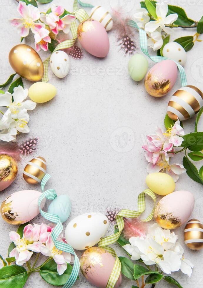 Easter eggs frame on a concrete background with flowers and feathers photo