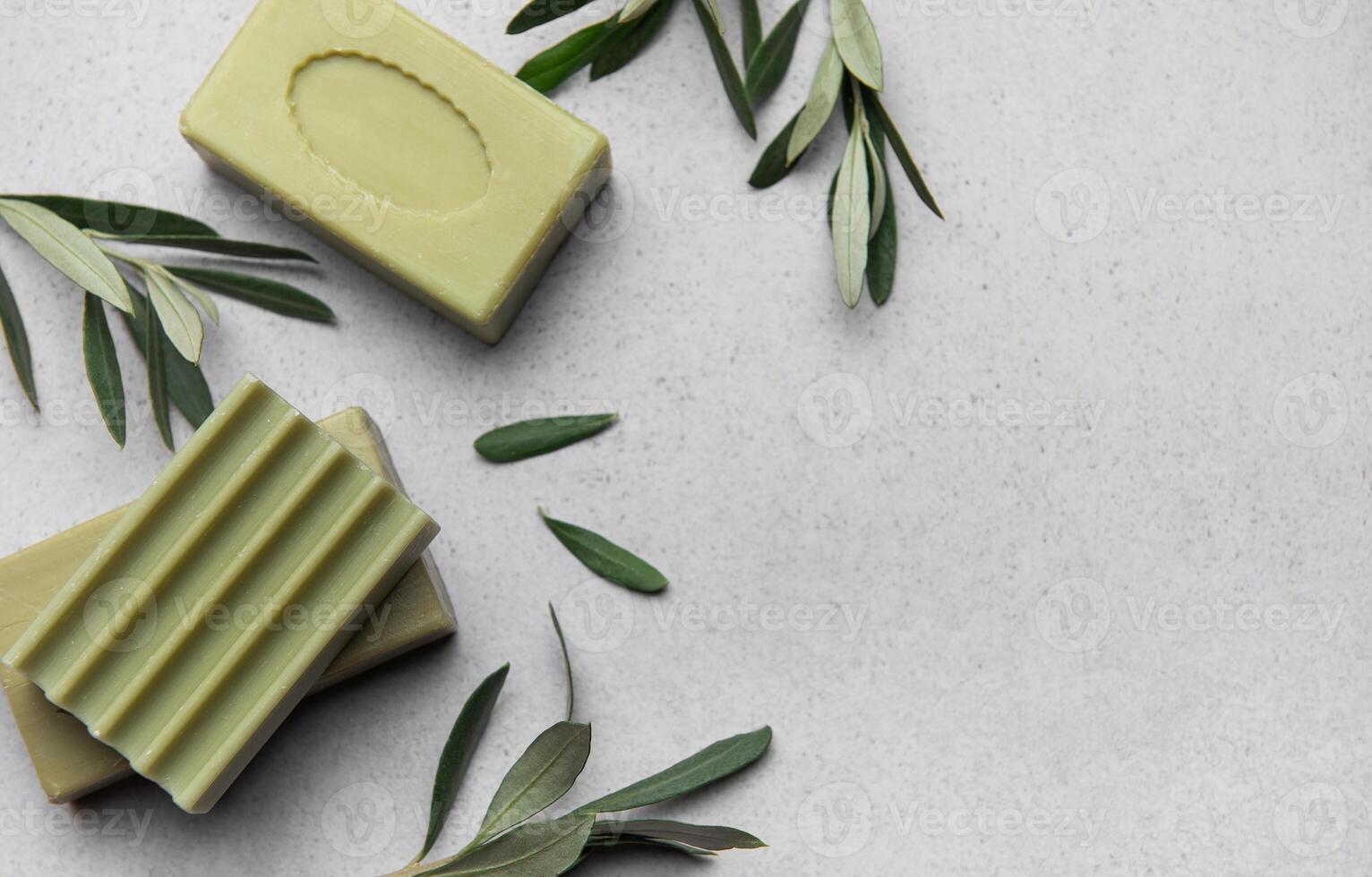 Olive soap bars and olive branches resting on marble countertop photo