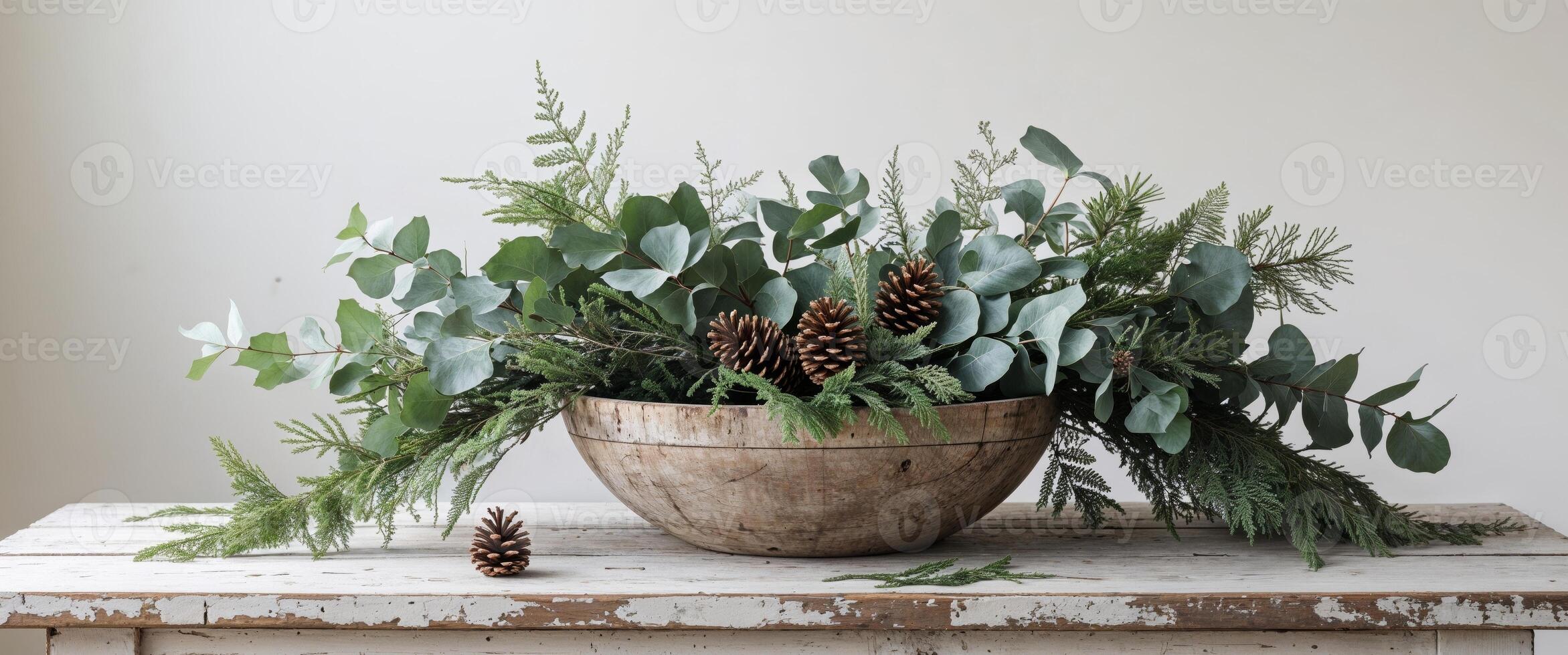 Cozy Holiday Decor Featuring Fresh Greenery and Pine Cone in a Natural Wooden Bowl on Rustic Table. photo