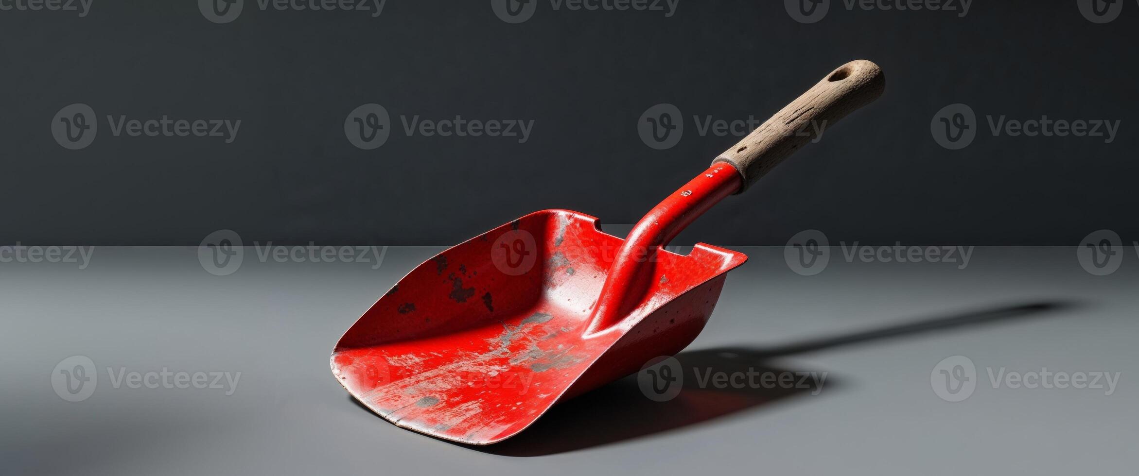 there is a red shovel with a wooden handle on a black background. photo