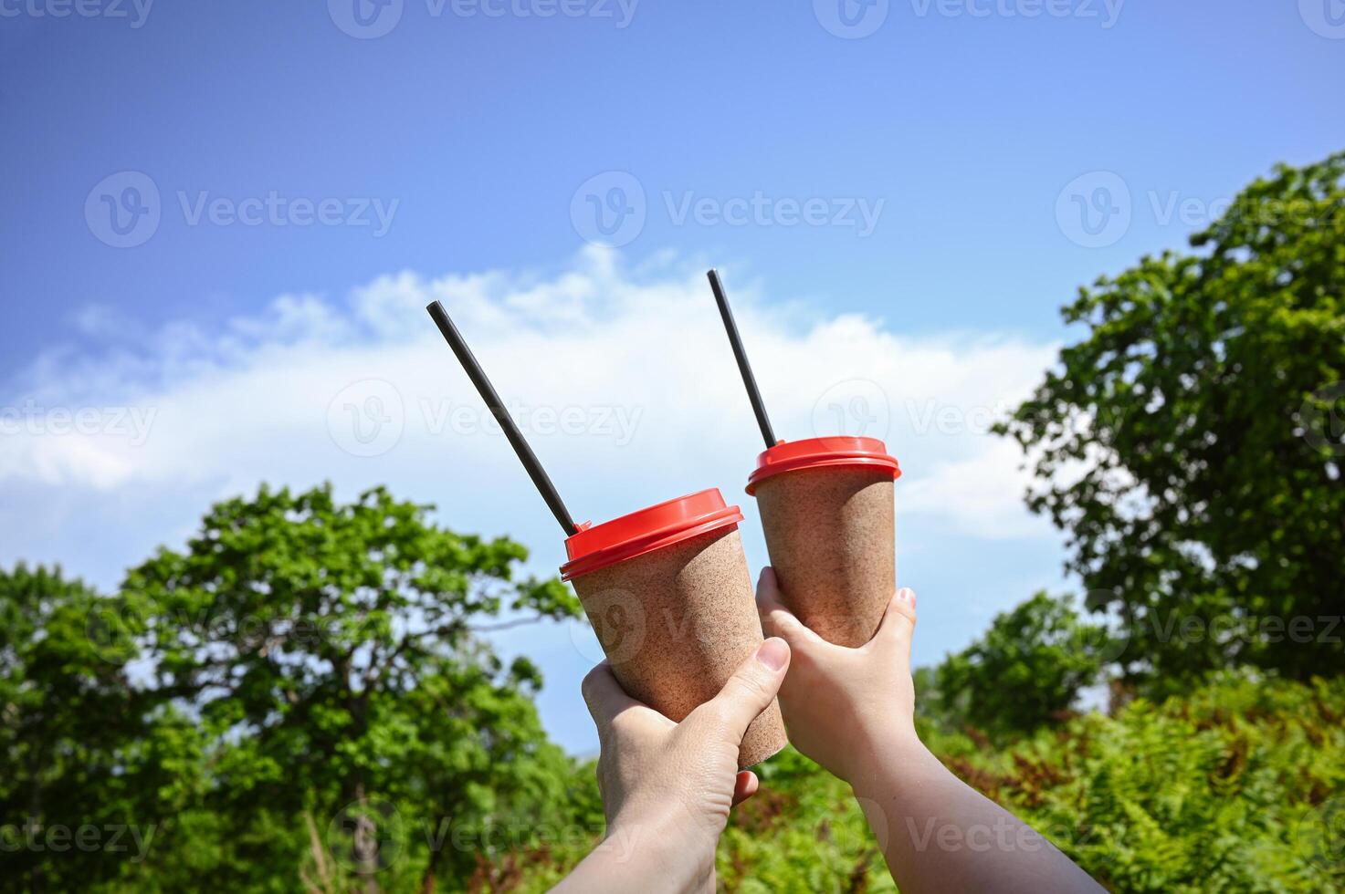 Coffee from a paper cup, relaxing in a sunny spring green city park in nature. Two cups. The concept of urban leisure. photo