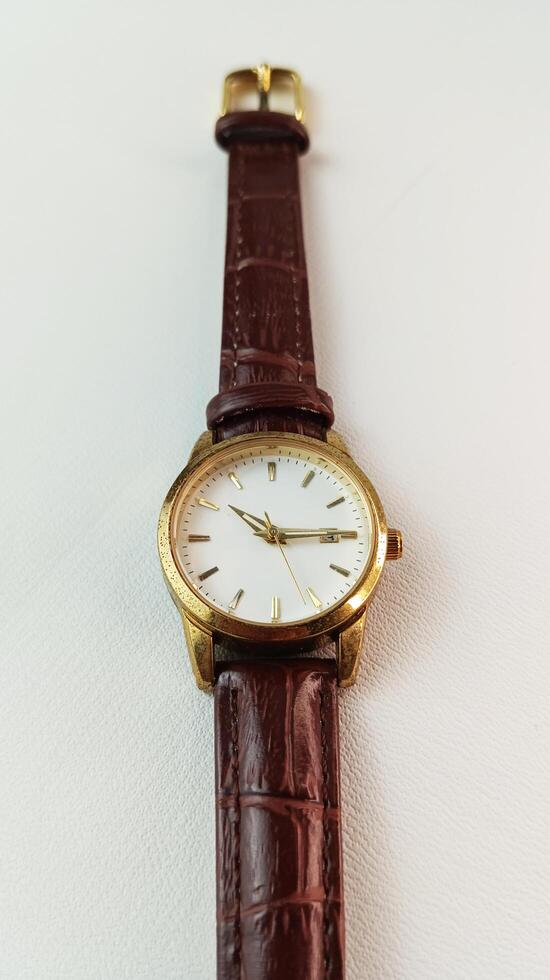 White women's analog watch, gold frame and brown strap. photo