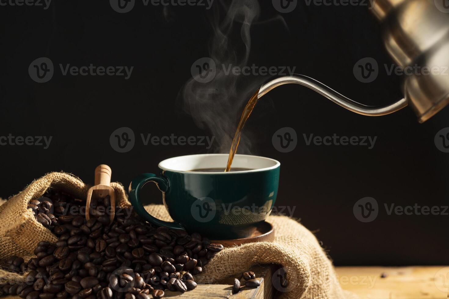 Pouring black coffee into a green coffee cup There are roasted coffee beans arranged on the table. with a black background and dark colors photo
