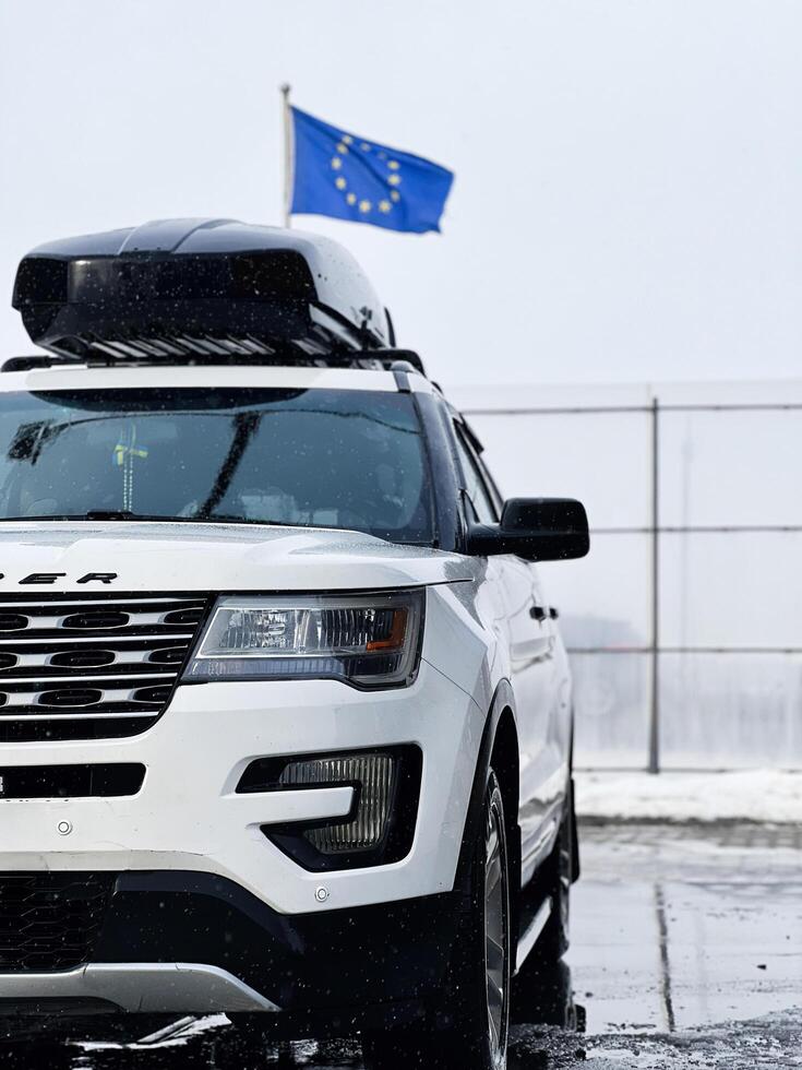 Kyiv, Ukraine - March 04, 2025- White modern Ford Explorer SUV in snow with EU flag in background photo