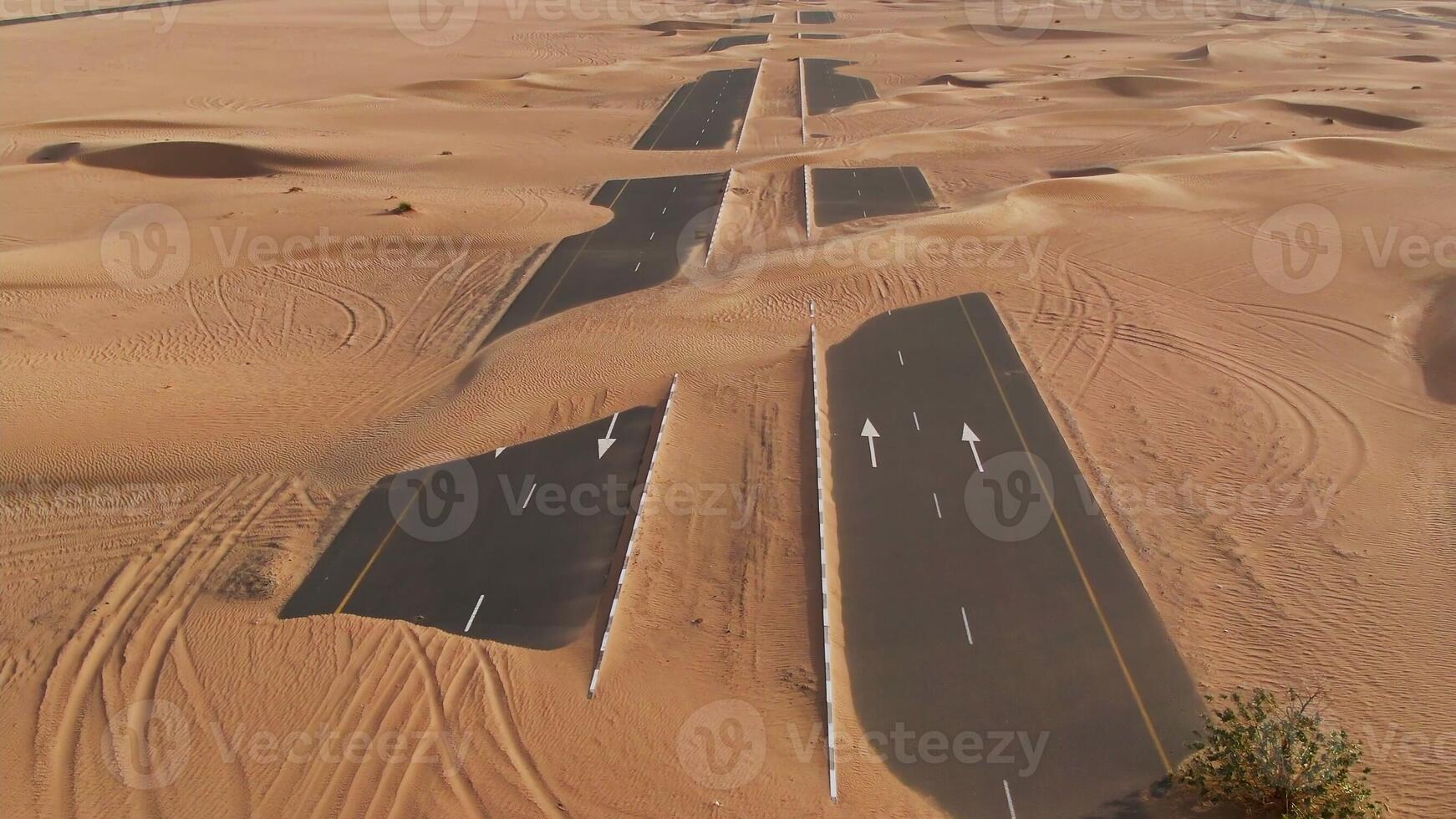 A desert road with sand dunes and trees in the background photo