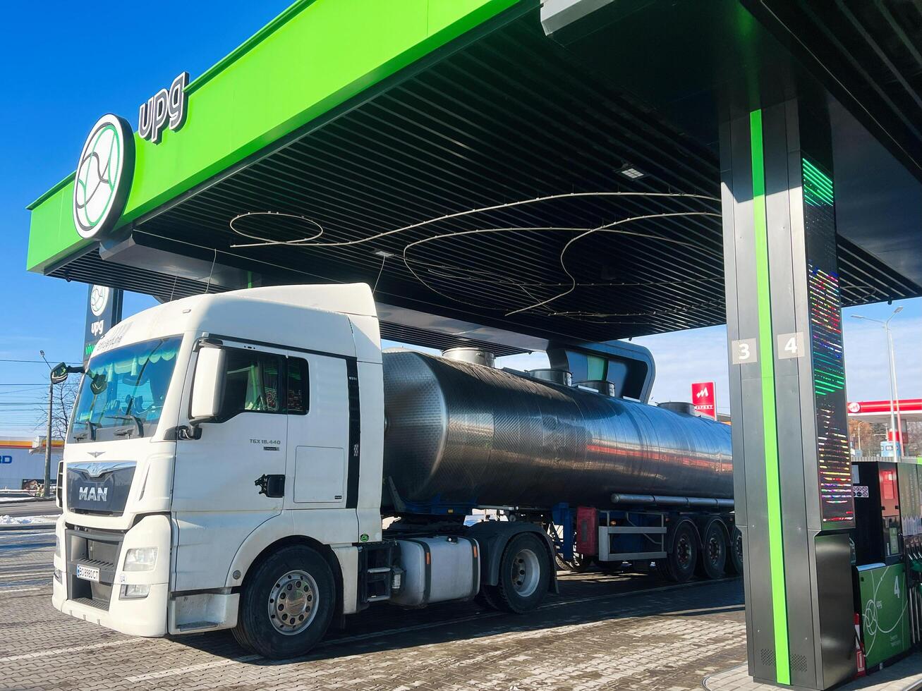 Kyiv, Ukraine - March 04, 2025- Fuel tanker Man truck refueling at a modern station under clear blue skies photo