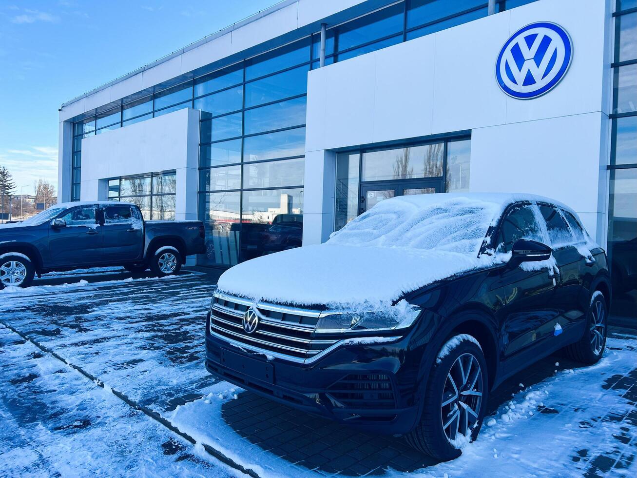 Kyiv, Ukraine - March 04, 2025- Snow-covered Volkswagen cars parked outside a commercial vehicle dealership on a winter day photo