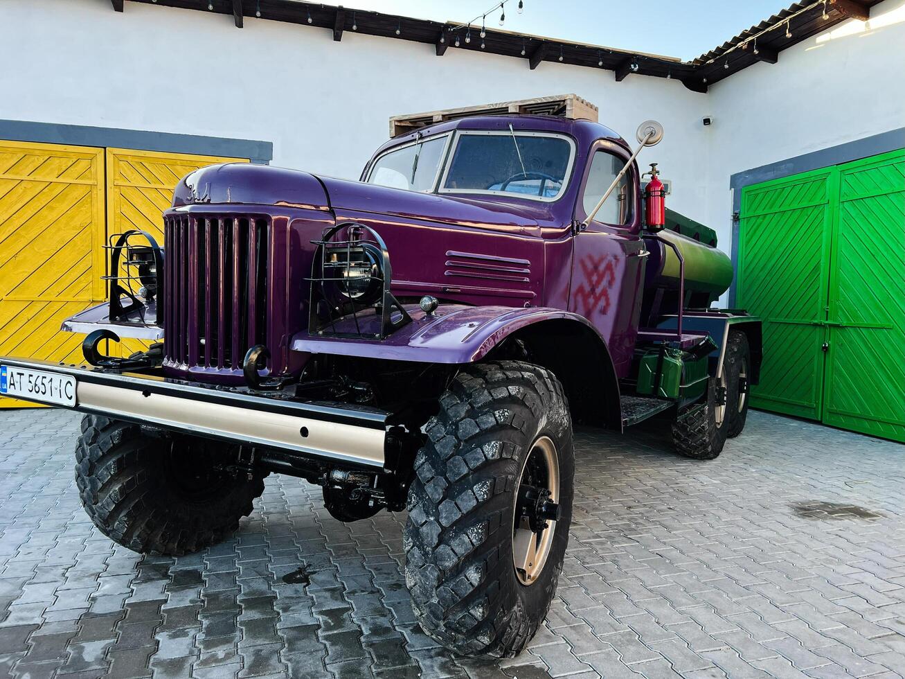 Kyiv, Ukraine - March 04, 2025- Customized vintage truck in a courtyard with colorful wooden doors photo