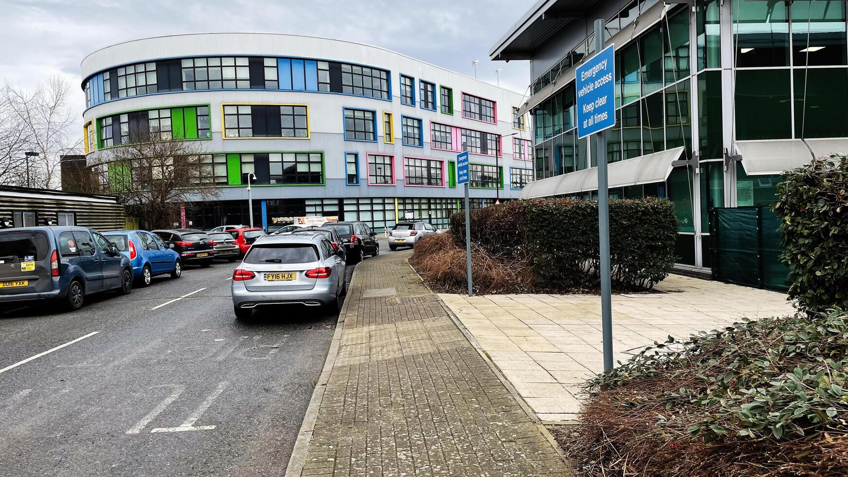London, UK - March 02, 2025- Modern educational building exterior with vibrant facade and parking area photo