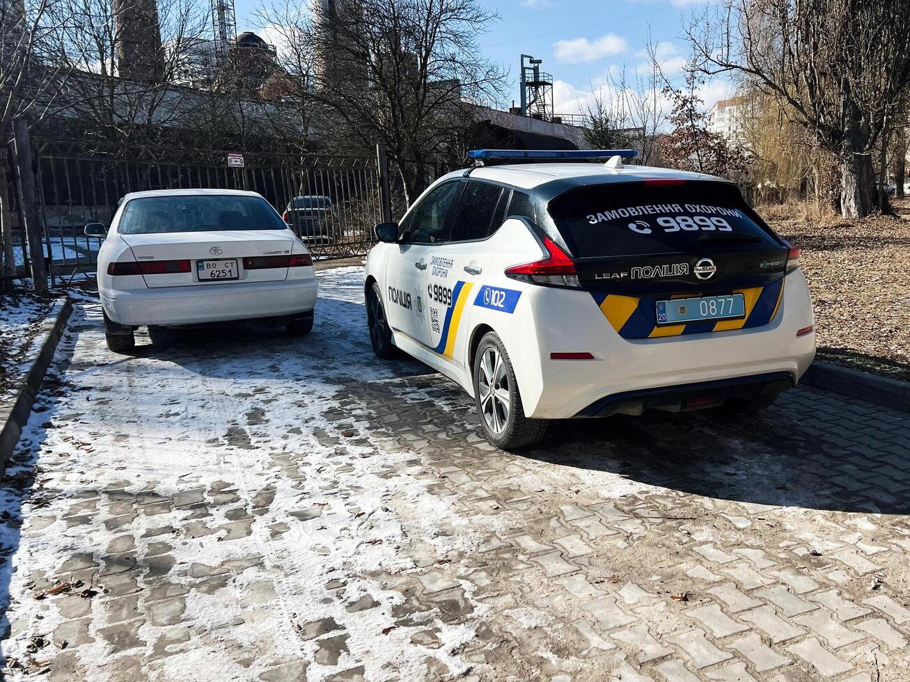 Kyiv, Ukraine - March 04, 2025- Police car parked near a white sedan on a winter snowy day photo
