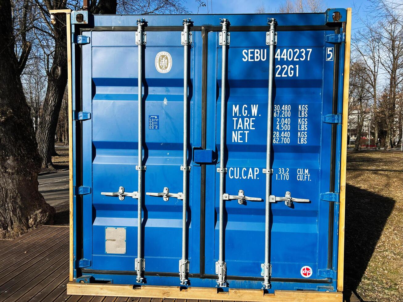 Kyiv, Ukraine - March 04, 2025- Blue shipping container in a park with trees during clear sunny weather photo