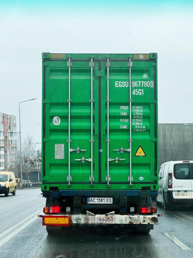 Kyiv, Ukraine - March 04, 2025- Green shipping container truck on a highway during overcast weather photo