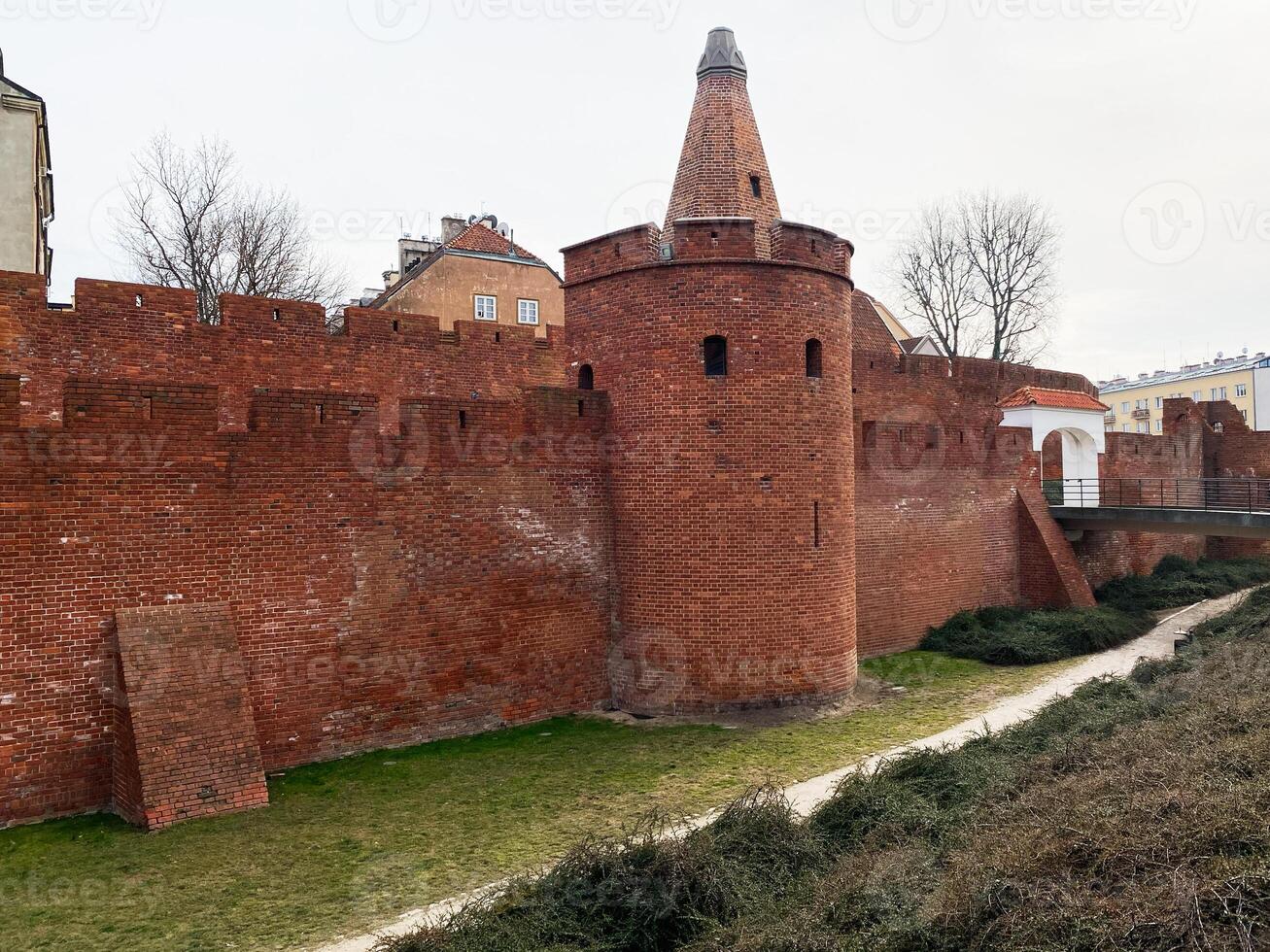 Historic brick city walls and tower in Warsaw, Poland during overcast day photo