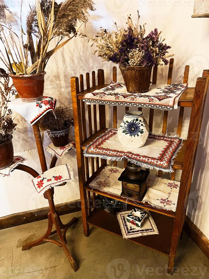 Rustic wooden shelf decorated with traditional embroidery and dried floral arrangements photo