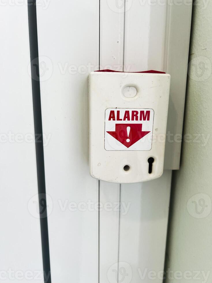 Wall-mounted emergency alarm device with keyhole and warning label photo