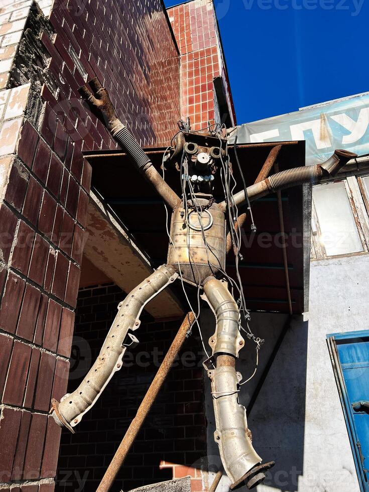 Metal Sculpture of Human Figure With Chains Posed Against Brick Building photo