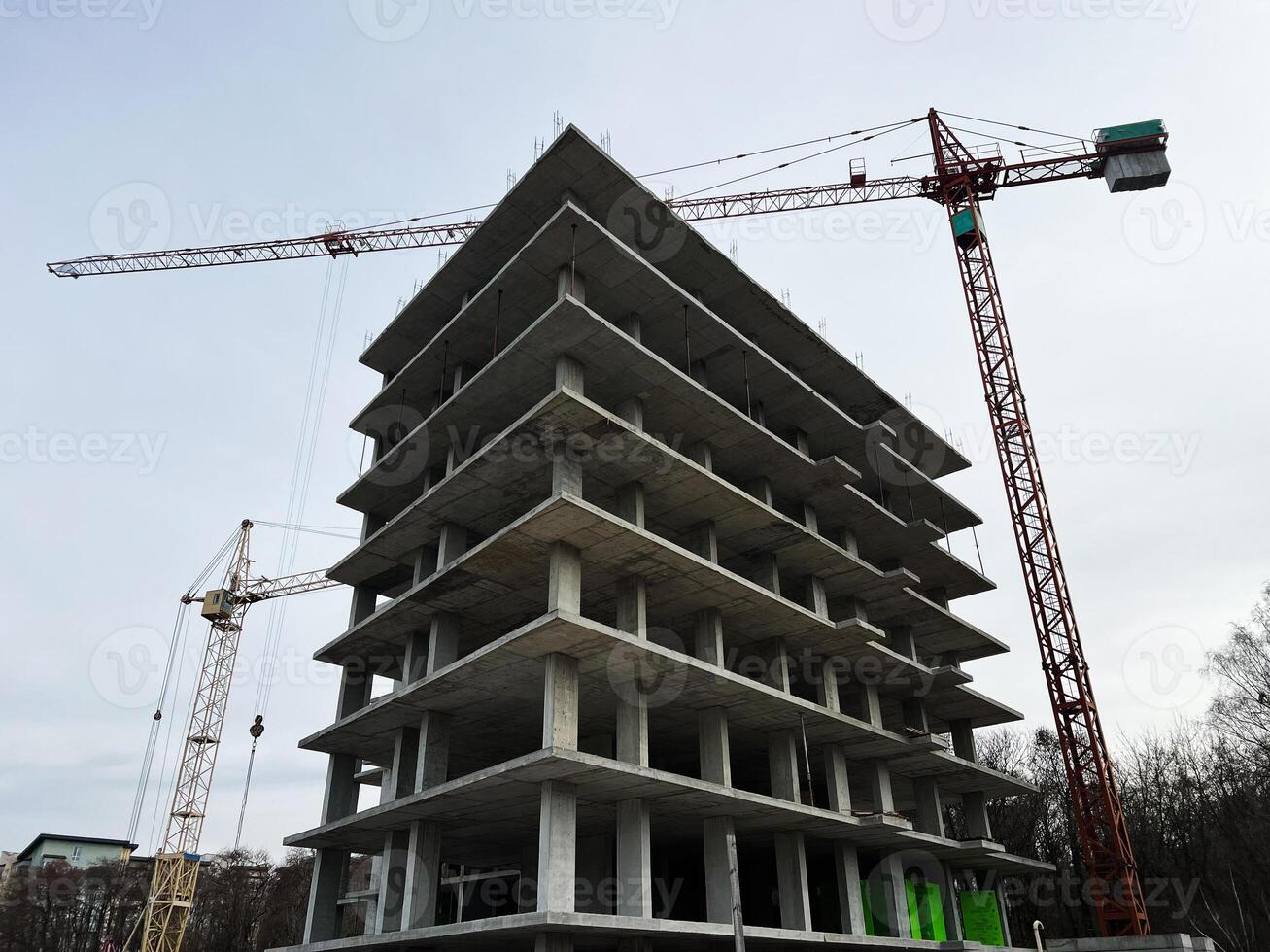 Modern construction site with building framework and cranes under cloudy sky photo