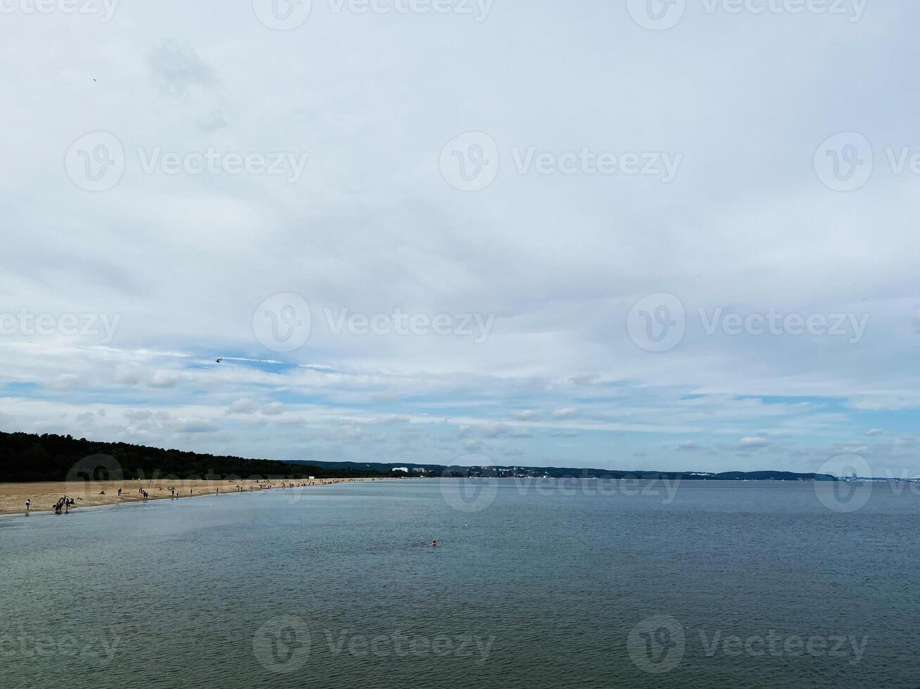 Scenic beach view with calm waters and cloudy blue sky in summer photo