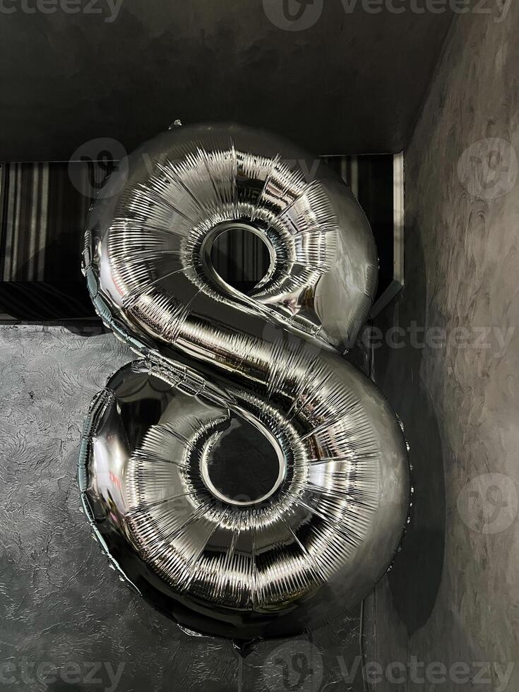 Gleaming silver foil balloon shaped as the number eight indoors photo