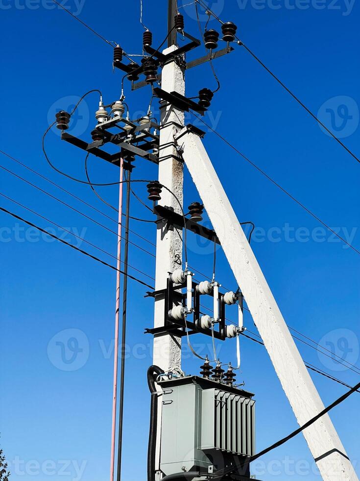 Electricity Transmission Pole with Wires and Transformers Under a Clear Blue Sky photo