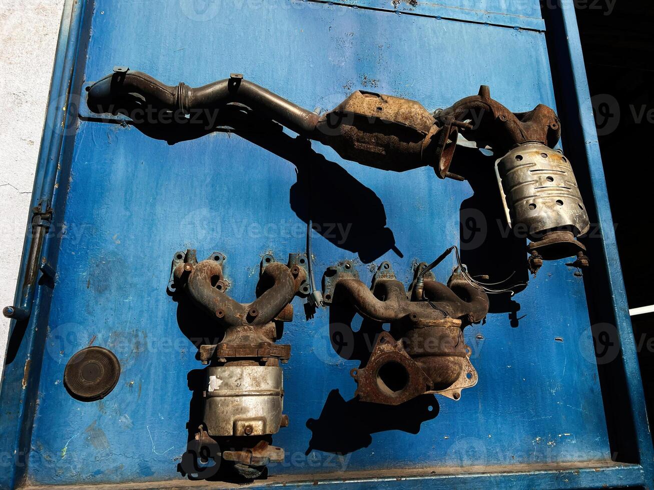 Various Car Exhaust System Components Displayed Against a Blue Metal Background photo