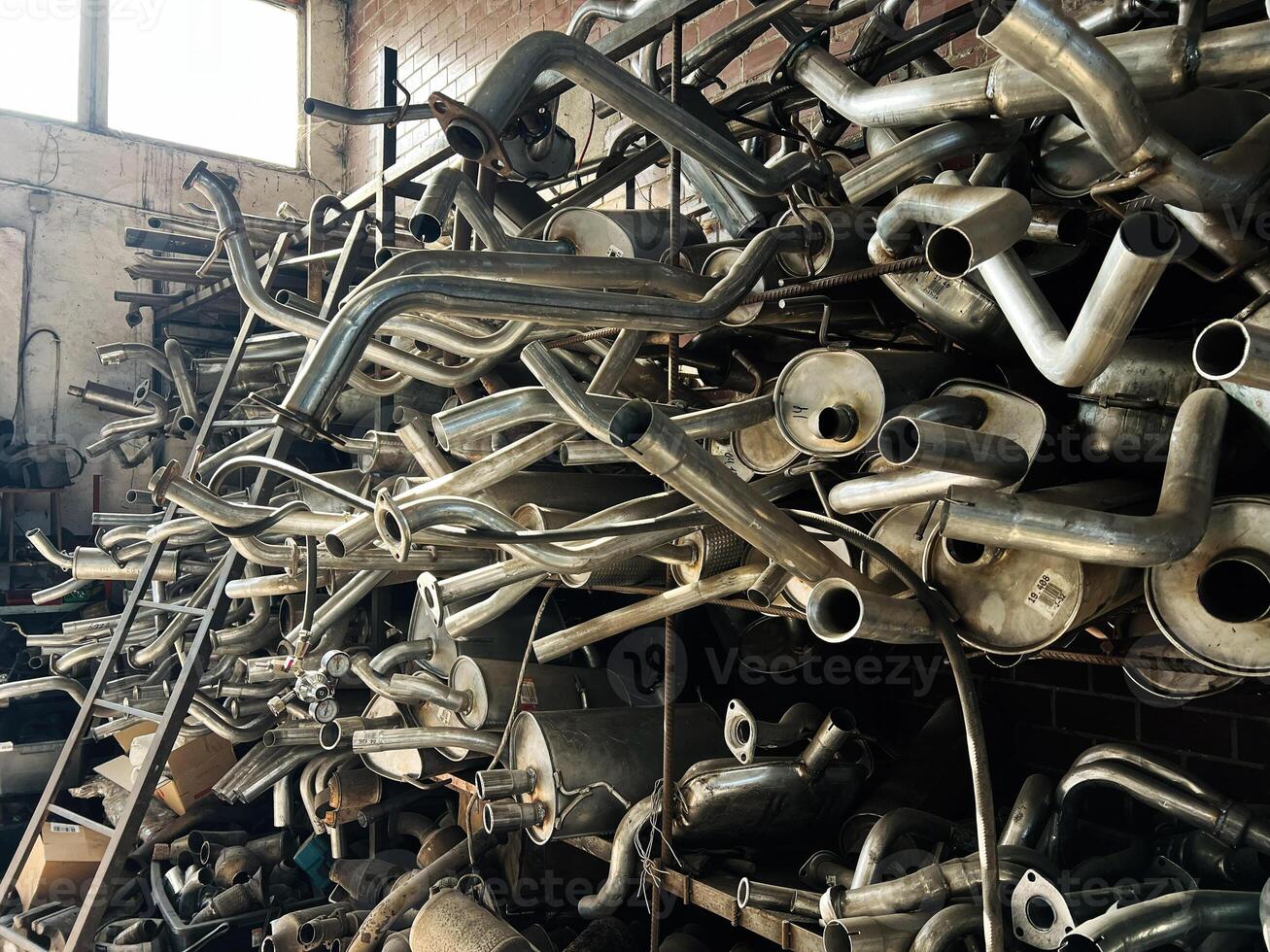 Stack of exhaust pipes and mufflers in a workshop environment for cars photo