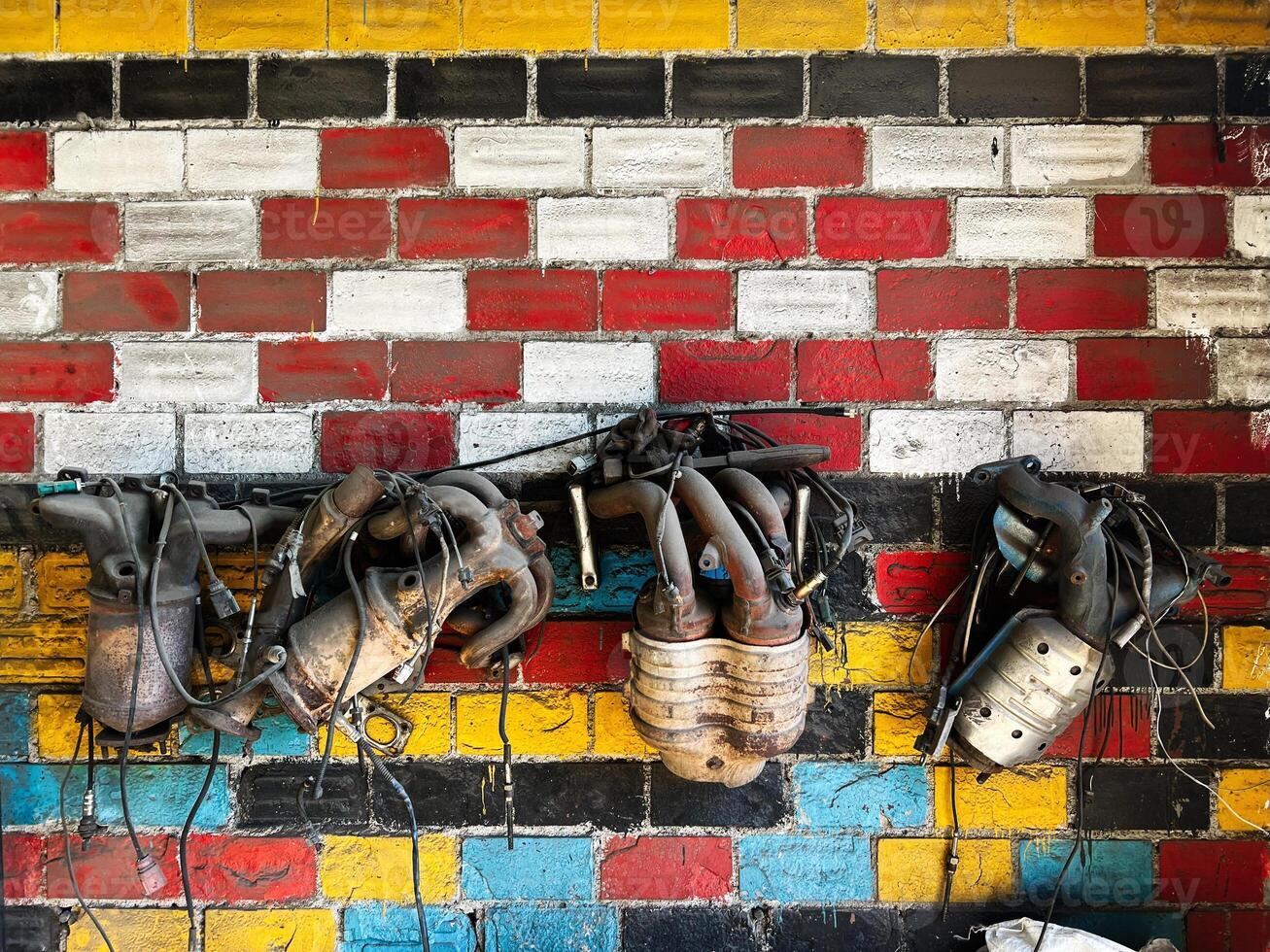 Old mechanical parts hanging on a colorful brick wall in a garage photo