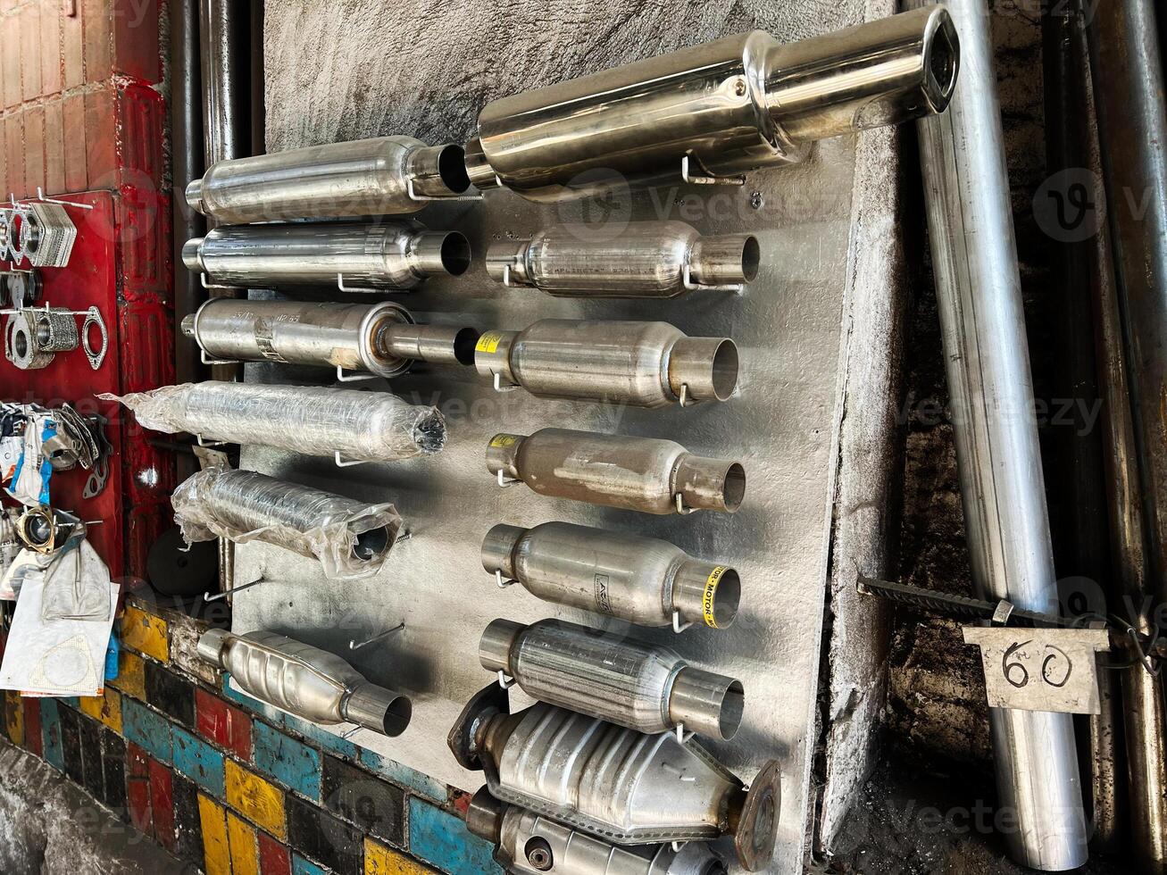 Various metallic exhaust pipes and components displayed on a garage wall photo