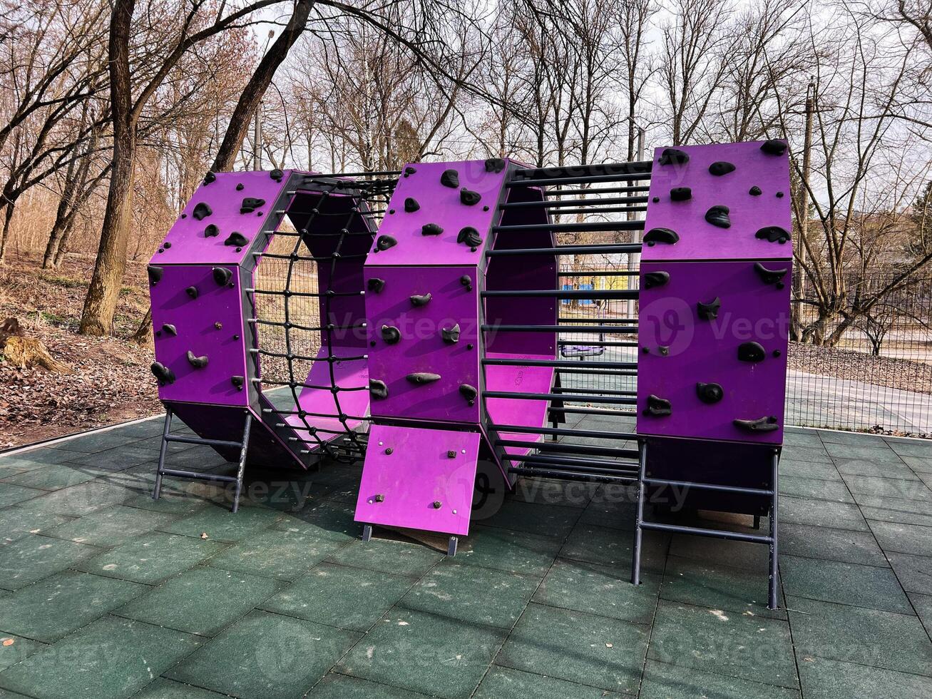 Colorful climbing structure in an outdoor playground surrounded by trees photo