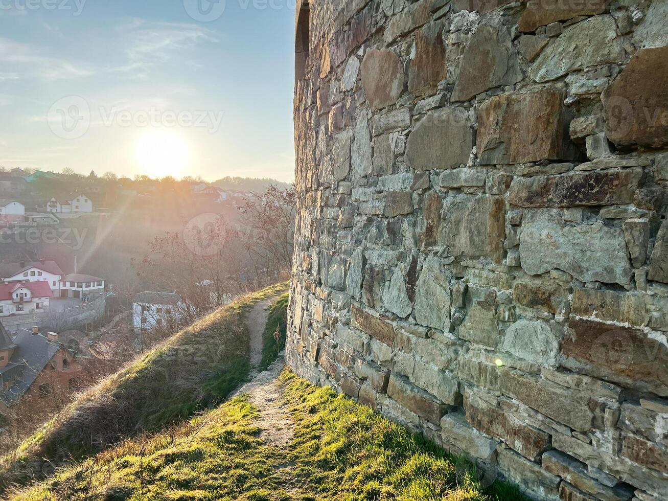 Stone wall overlooking a village bathed in the golden rays of sunset photo
