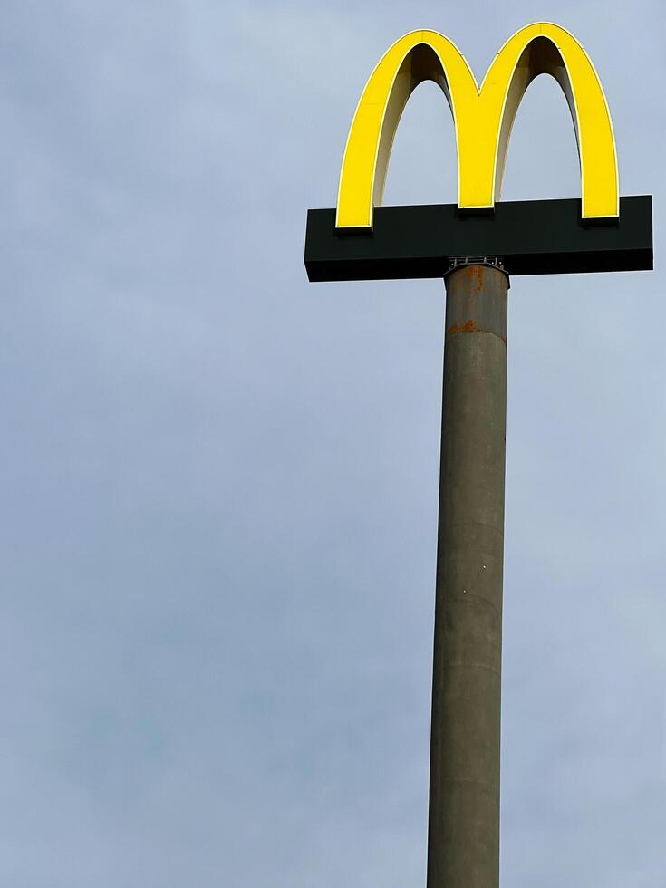 Lviv, Ukraine - March 12, 2025 - Tall signpost McDonald's with a vibrant yellow symbol against an overcast sky photo