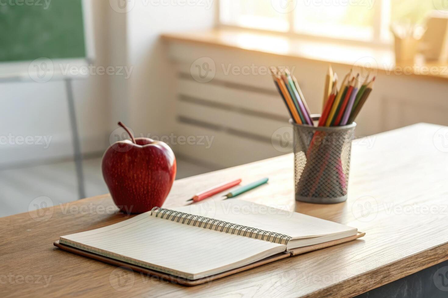 Back to school essentials with an apple, notebook, and colored pencils on a desk near a window photo