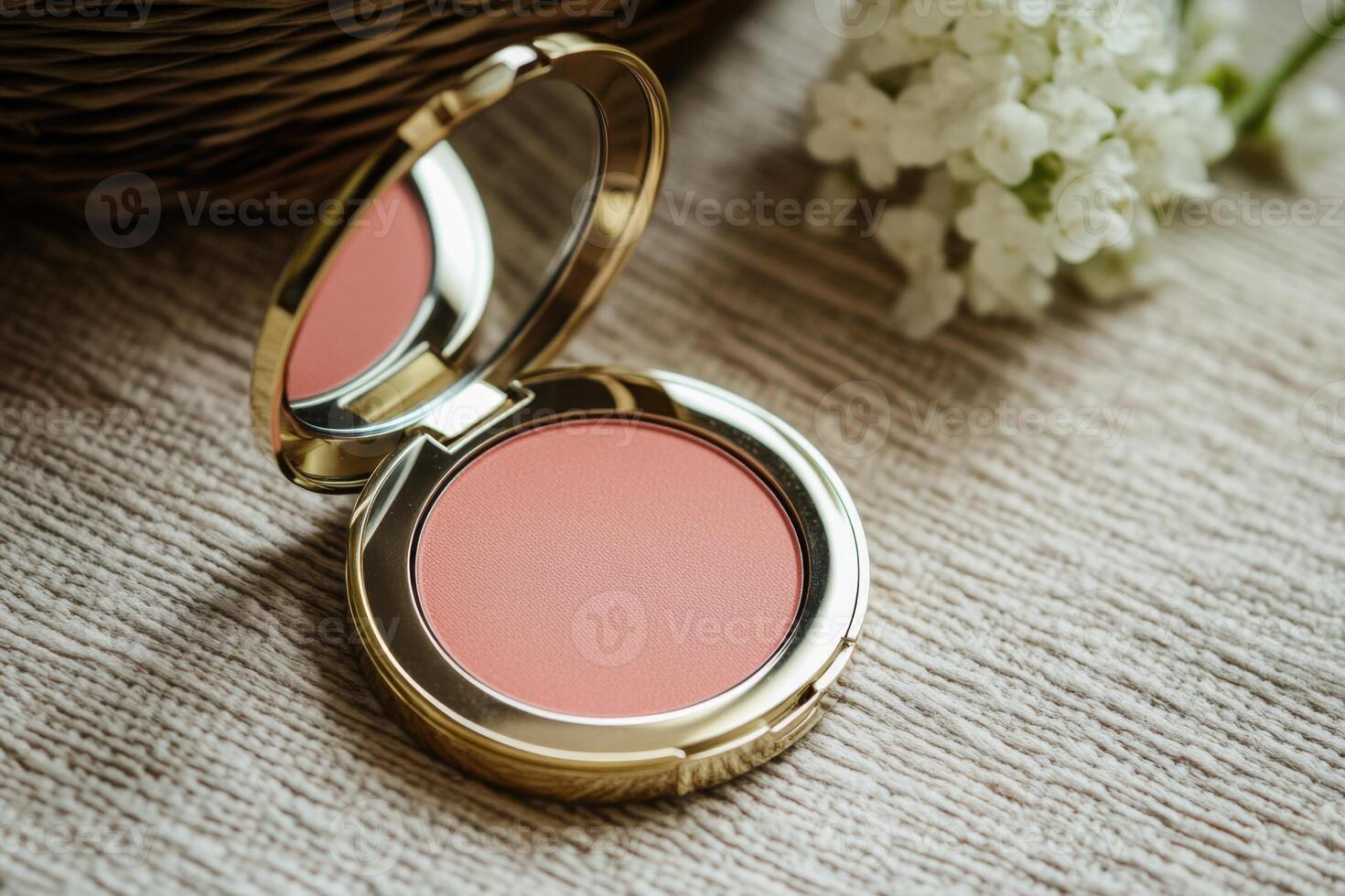 A small pink compact powder sits on a table next to a white flower photo