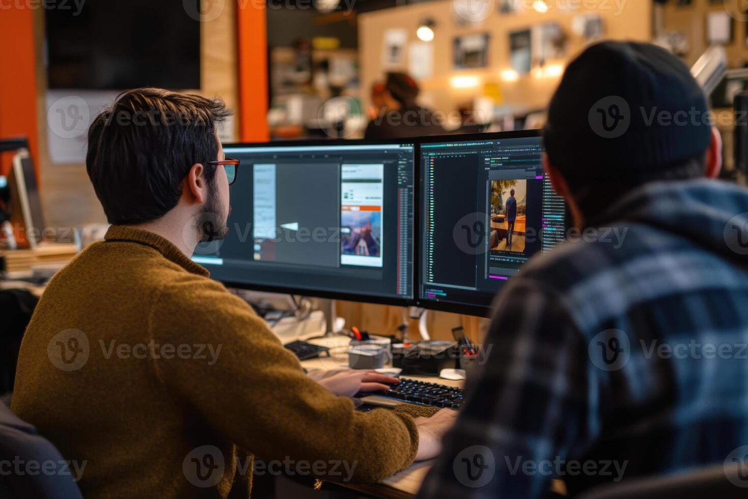 Two men are working on a computer screen, one of them wearing a brown sweater photo