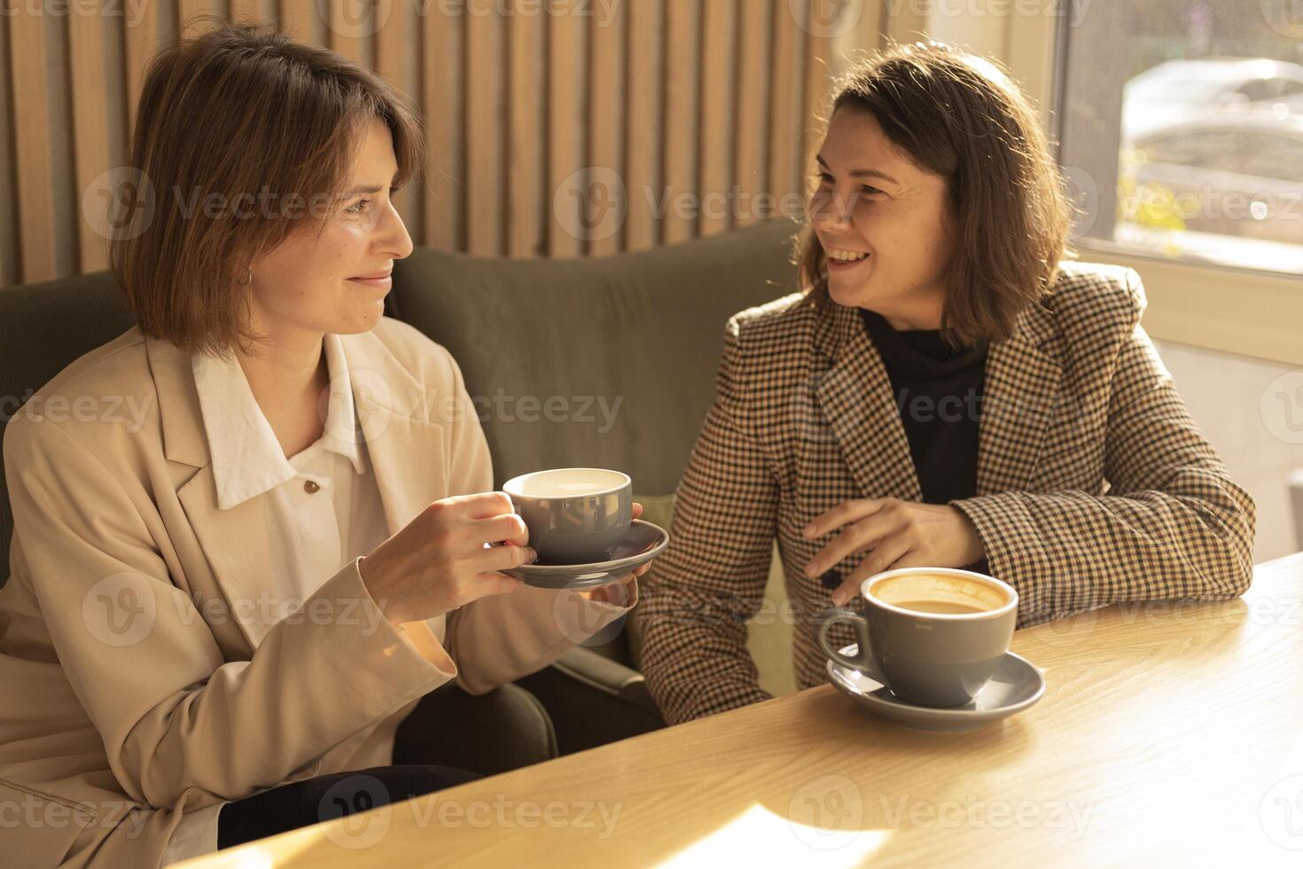two women talk over coffee in a cafe and smilling photo
