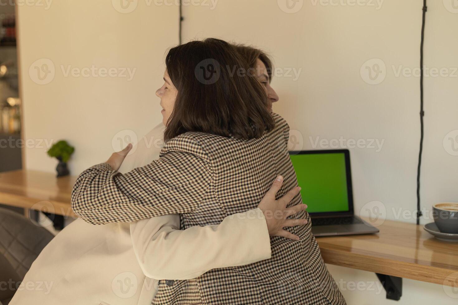 successful project, two women were working at computers and joyfully hugging photo