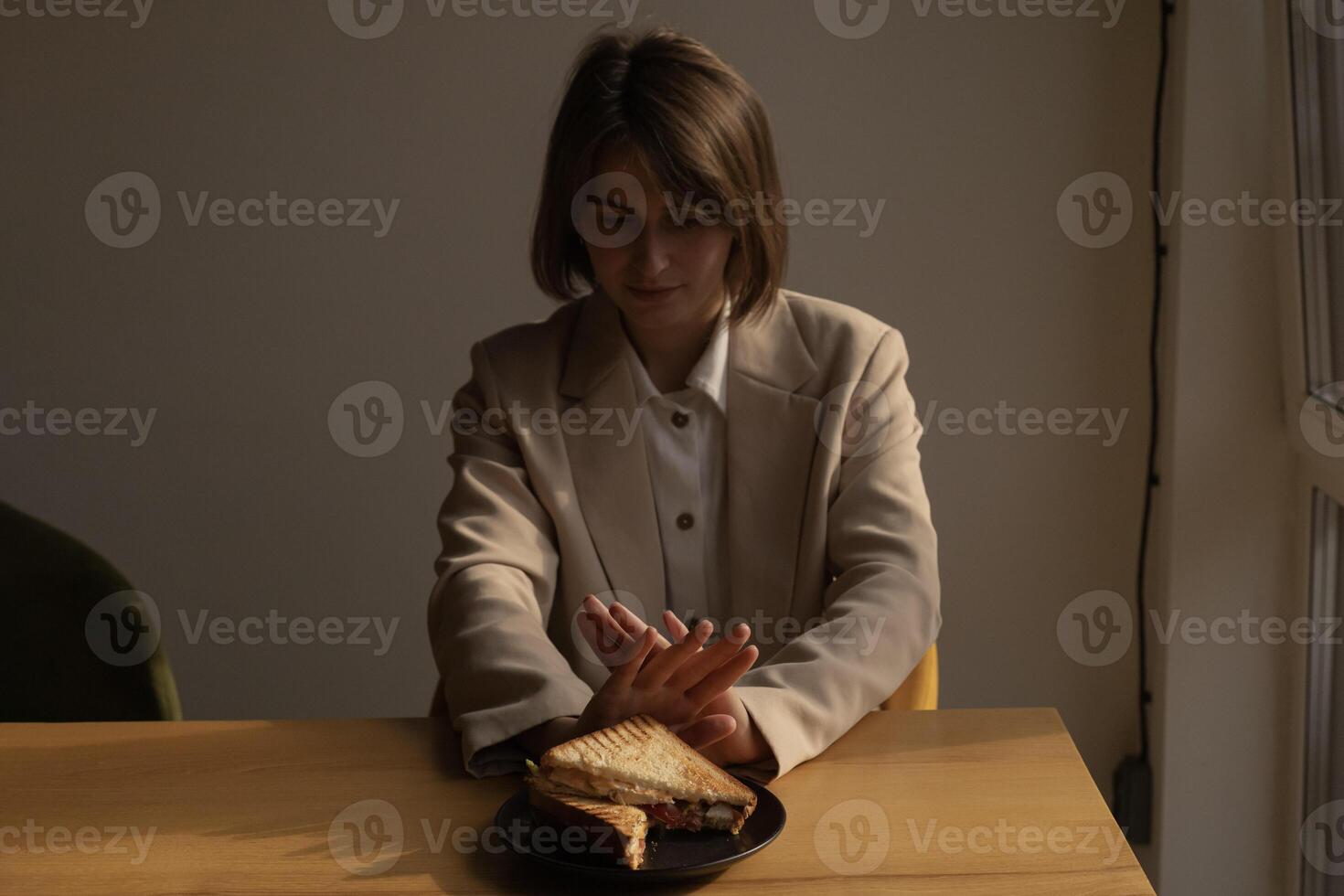 woman pushes a plate of sandwiches away from her, refusal to eat, diet, weight loss, eating disorder photo
