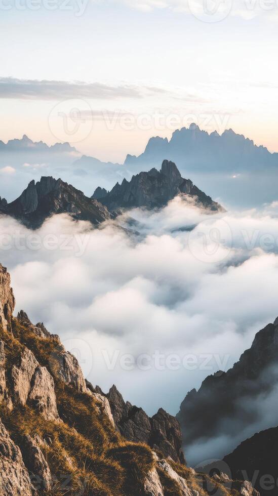 Jagged mountain peaks rise above cloud cover at sunrise photo