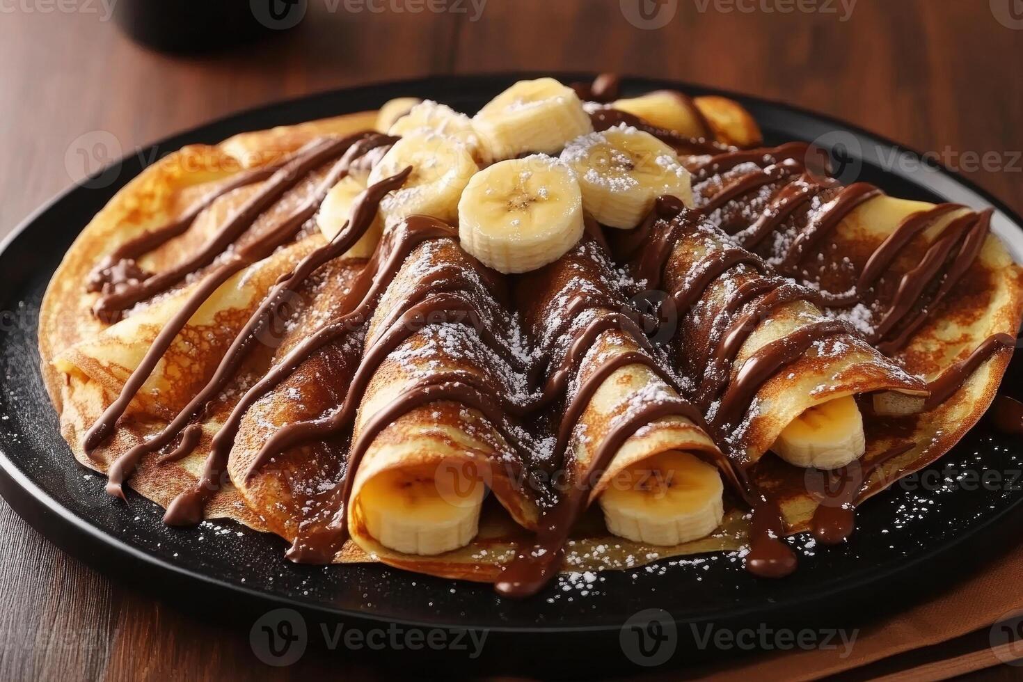 Banana crepes with chocolate drizzle and powdered sugar photo