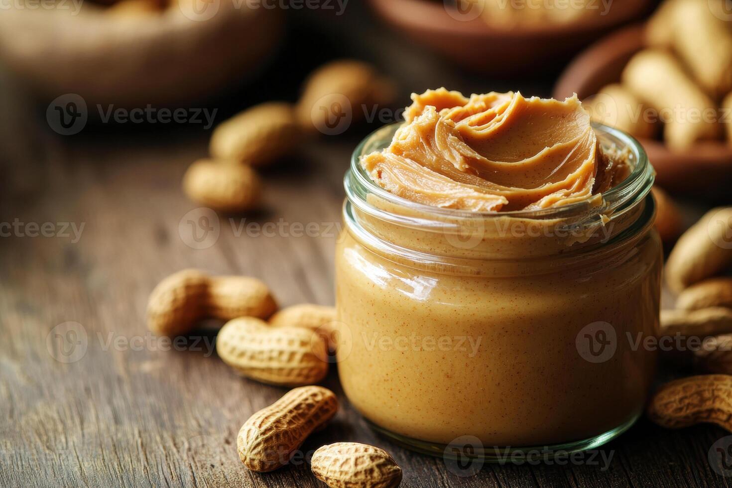 Creamy peanut butter in jar surrounded by peanuts on wooden table photo