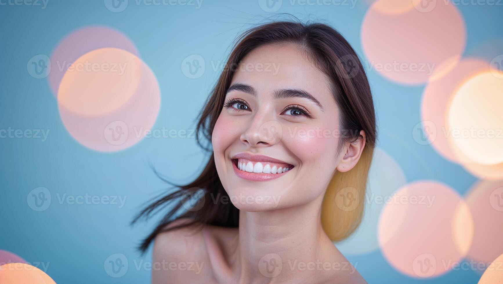 Smiling young woman with natural beauty and glowing skin against a soft blue background photo