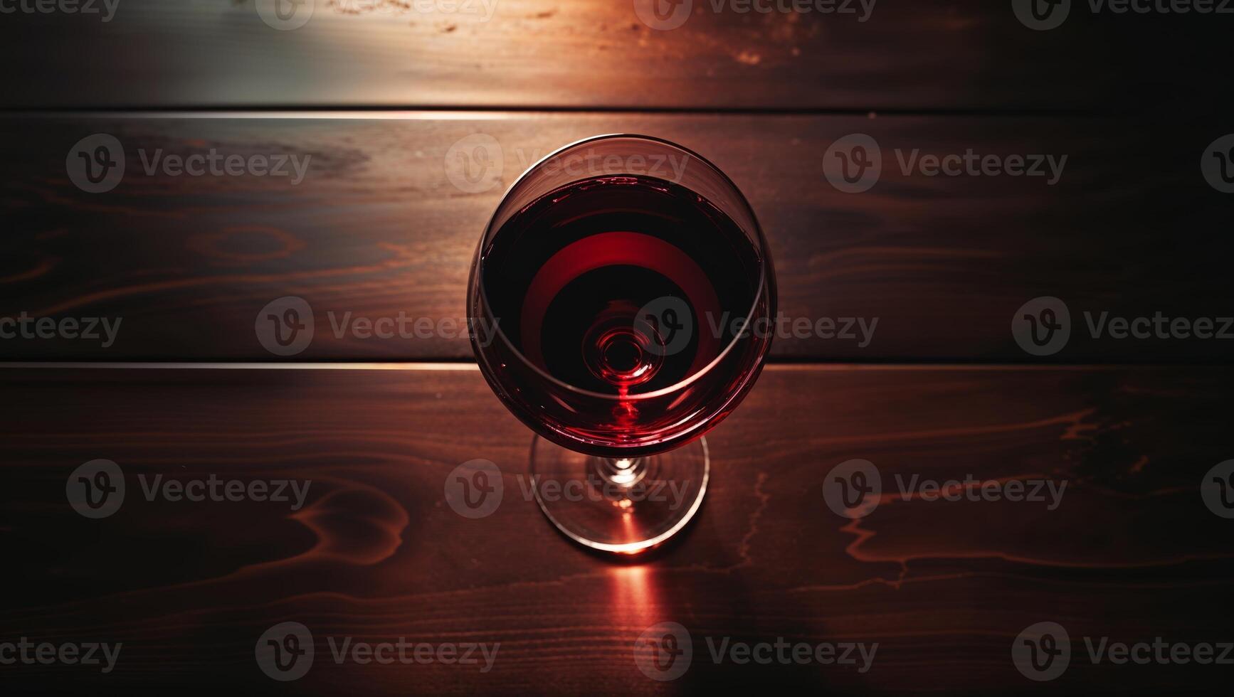 Red wine in a glass on a wooden table illuminated by soft light for an elegant evening atmosphere photo