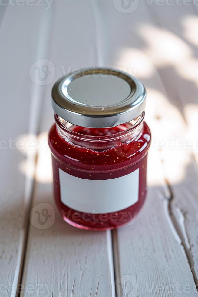 Homemade raspberry jam in a glass jar placed on a rustic wooden table in bright natural light photo