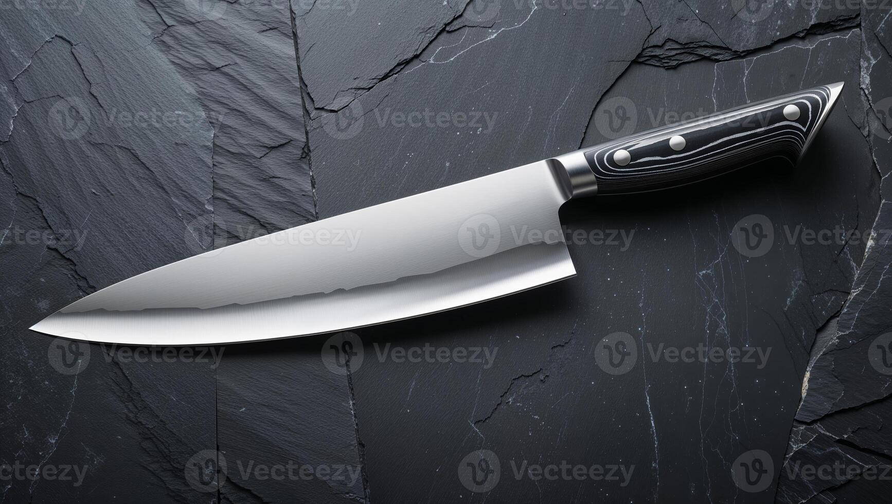 Chef's knife resting on a slate surface, highlighting its sharp blade and ergonomic handle photo