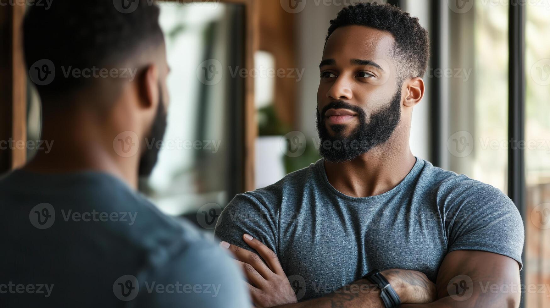 Man reflecting on personal growth while standing in front of a mirror in a well-lit room photo