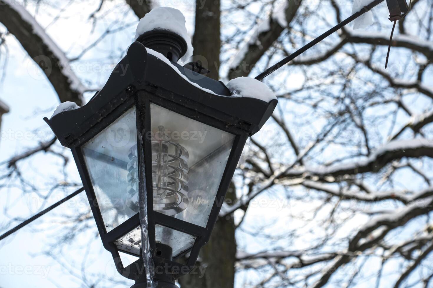 Vintage street lamp with icicle in winter sunlight gorizontal photo