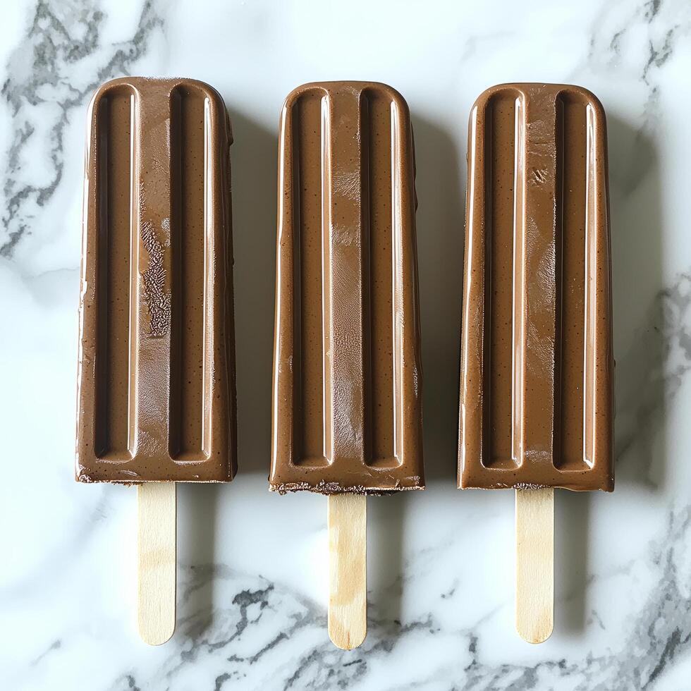 Three Chocolate Popsicles On Marble Surface photo
